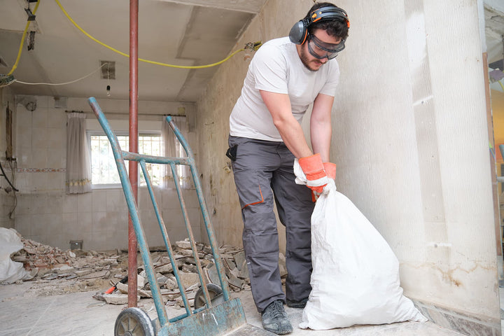 Mann mit Bauschutt in einem Sack bei der Badsanierung