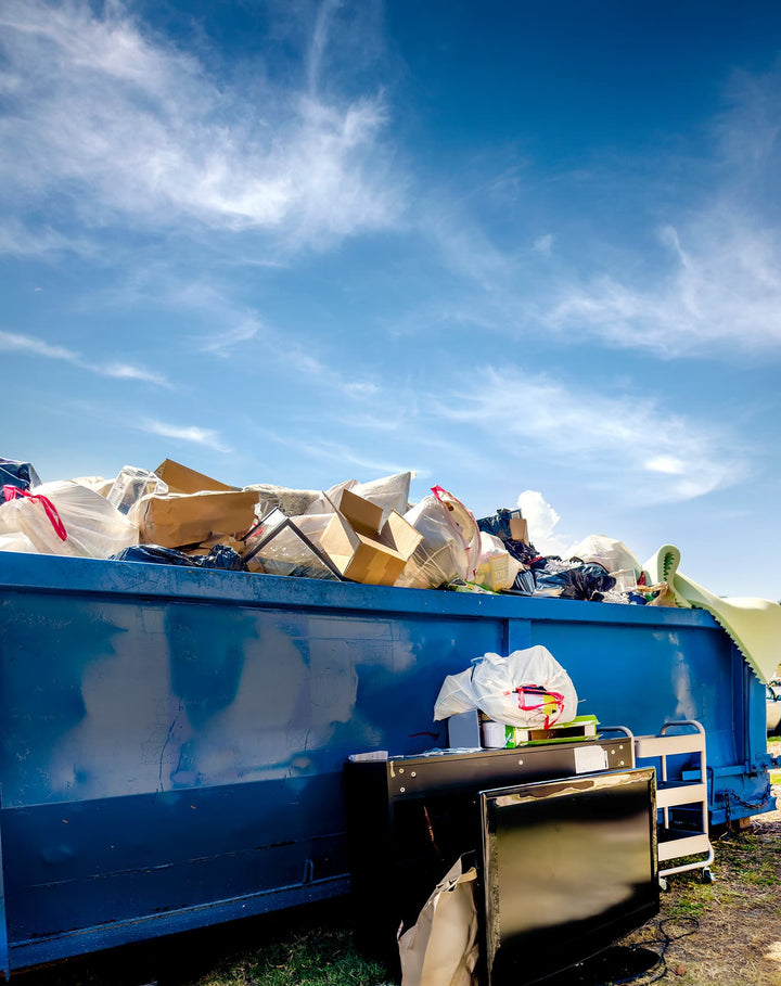 Großer Abfallcontainer mit Papier und Pappe vor blauem Himmel